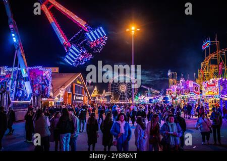 Stuttgart, Allemagne. 06 octobre 2024. Les visiteurs affluent dans la soirée au 177e Cannstatter Volksfest illuminé sur le Cannstatter Wasen. Le 'Wasen' est le deuxième plus grand festival folklorique en Allemagne après l'Oktoberfest de Munich. Crédit : Christoph Schmidt/dpa/Alamy Live News Banque D'Images