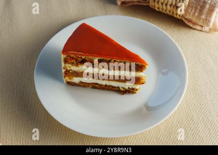 Délicieuses couches de gâteau aux carottes avec glaçage crémeux servi sur une assiette blanche dans un cadre de salle à manger confortable Banque D'Images