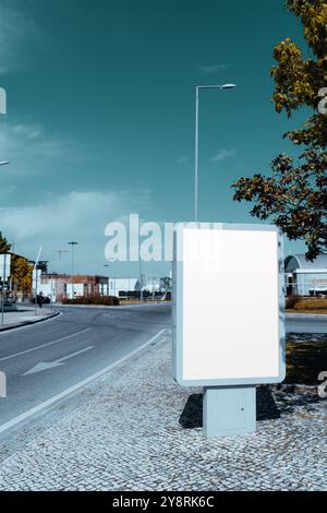 Une maquette de panneau d'affichage de publicité extérieure verticale vierge sur un coin de rue moderne avec un trottoir propre. Idéal pour afficher du contenu promotionnel ou un soutien-gorge Banque D'Images