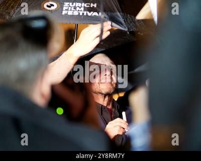 ZURICH / SUISSE, 6 octobre 2024. Ralf Fiennes sur le tapis vert pour 'Conclave' signant des autographes sous la pluie au 20e Festival du film de Zurich au Festival Centre du 6 octobre 2024. Crédits : Walter Gilgen crédit : Walter Gilgen/Alamy Live News Banque D'Images