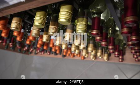 La vue avec une chambre de mouvement sur de nombreuses bouteilles de vin debout dans l'usine est prête à la vente. Les rangées de bouteilles en verre de la collection de rouge Banque D'Images