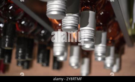 La vue avec une chambre de mouvement sur de nombreuses bouteilles de vin debout dans l'usine est prête à la vente. Les rangées de bouteilles en verre de la collection de rouge Banque D'Images