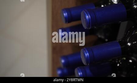 La vue avec une chambre de mouvement sur de nombreuses bouteilles de vin debout dans l'usine est prête à la vente. Les rangées de bouteilles en verre de la collection de rouge Banque D'Images