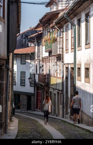 Pittoresque ruelle étroite avec de petites maisons résidentielles dans le centre-ville de Viana do Castelo, deux touristes marchant par, Portugal Banque D'Images