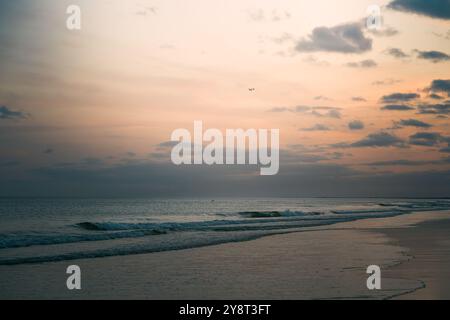 Vagues légèrement floues roulant sur le rivage au crépuscule. Banque D'Images