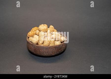 Cacahuètes décortiquées dans un bol en bambou sur un sol gris. De délicieuses noix. Banque D'Images