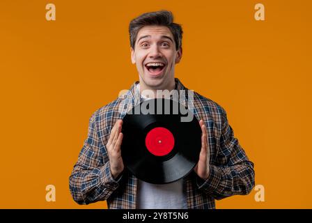 Homme mature élégant avec disque vinyle sur jaune. Hobby, musique, collection Banque D'Images