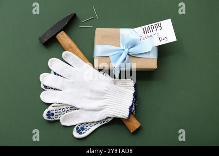 Boîte cadeau, gants, marteau et carte de voeux avec texte HAPPY PER'S DAY sur fond vert Banque D'Images