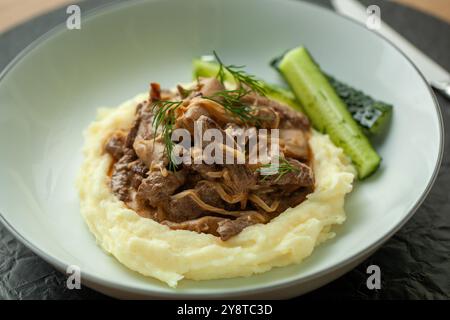 Délicieux stroganoff de bœuf avec purée de pommes de terre et cornichons servis dans une assiette Banque D'Images