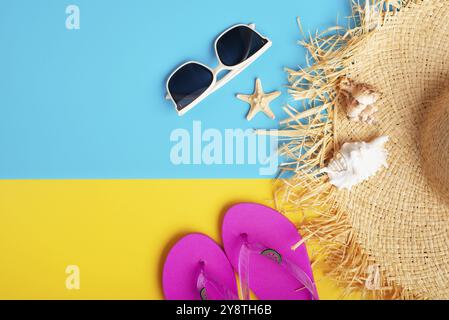 Chapeau de paille lunettes de soleil tongs et coquillages sur fond jaune et bleu planification de voyage de vacances maquette Banque D'Images