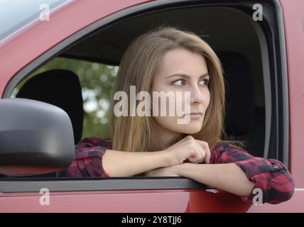 Jeune femme regardant par la fenêtre de voiture Banque D'Images