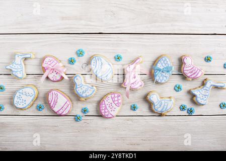 Biscuits givrés de Pâques en forme de poule d'oeuf et de lapin sur fond de table en bois blanc avec des saupoudrages de sucre. Maquette horizontale posée à plat Banque D'Images