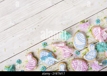 Biscuits givrés de Pâques en forme de poule d'oeuf et de lapin sur fond de table en bois blanc avec des saupoudrages de sucre. Maquette horizontale posée à plat Banque D'Images