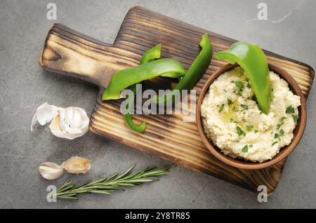 Vue sur la couche plate du plat à tremper Hummus aux légumes, surmontée de pois chiches et d'huile d'olive, servie avec des tranches de poivron vert Banque D'Images