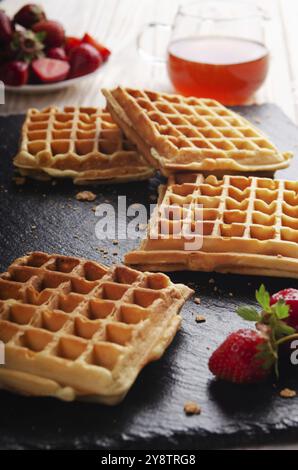 Gaufres belges faites maison sur un plateau en ardoise avec sirop d'érable et fraises à part Banque D'Images