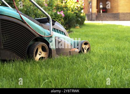 Motionnaire de pelouse sur l'herbe verte dans la maison en brique et en avant Banque D'Images