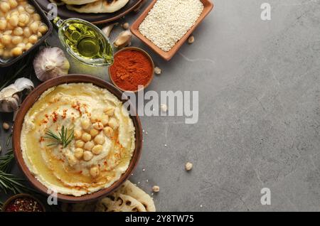 Houmous recouvert de pois chiches, huile d'olive et feuilles de coriandre verte sur table en pierre avec pain pita et épices de côté. Pose plate Banque D'Images