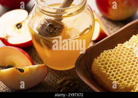 Pot Mason avec un pot au miel et des pommes rouges et un nid d'abeille sur une table de cuisine Banque D'Images