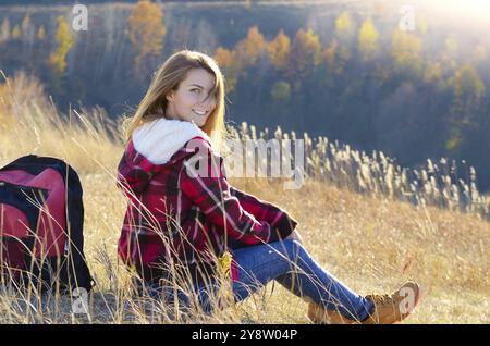 Jeune femme heureuse ayant du plaisir à l'extérieur assis sur le sommet de la colline. Concept de tourisme de randonnée Banque D'Images