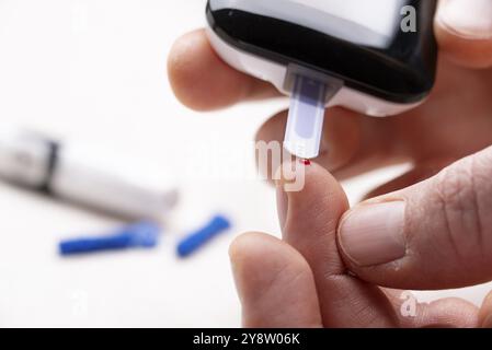 Doigts caucasiens avec goutte de sang prêt à faire le test de glucose à la maison par glucomètre gros plan vue Banque D'Images