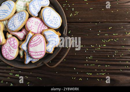 Saupoudrés de sucre et plateau métallique avec biscuits givrés de Pâques en forme de poulet à l'œuf et de lapin sur fond de table en bois.Maquette de pose à plat avec copie sp Banque D'Images