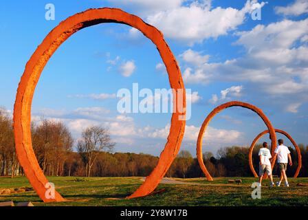 Un jeune couple marche pas dans les grands cercles du Gyre de Thomas Sayre sur le terrain de sculpture du North Carolina Museum à Raleigh Banque D'Images