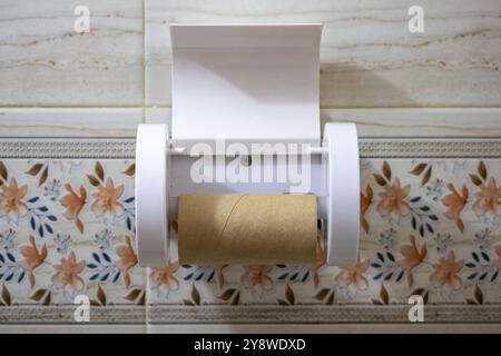 Support de papier hygiénique avec un cylindre en carton vide sur fond de carreaux de céramique. Hors du rouleau de papier toilette dans la salle de bain. Banque D'Images