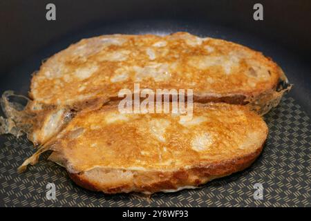 Deux morceaux de pain grillé sont dans une casserole, dont l'un est légèrement brûlé. L'autre est brun doré. Banque D'Images