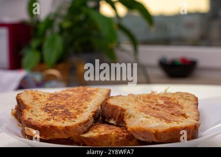 Trois tranches de pain grillé sont sur une assiette blanche. Les toasts ont une texture croustillante. L'assiette est placée sur une table. Banque D'Images