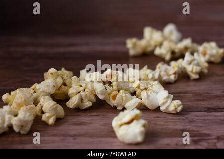 Un tas de pop-corn sur une table en bois. Le pop-corn est dispersé et une partie est cassée. Banque D'Images