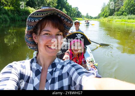 Couple homme et femme, enfant dans un chapeau de pirate, selfies sont heureux en famille kayak voyage bateau à rames sur la rivière, randonnée aquatique, aventure estivale. Écologique a Banque D'Images