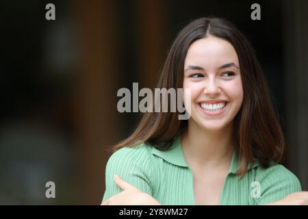 Femme heureuse souriant avec des dents parfaites regardant le côté dans la rue Banque D'Images