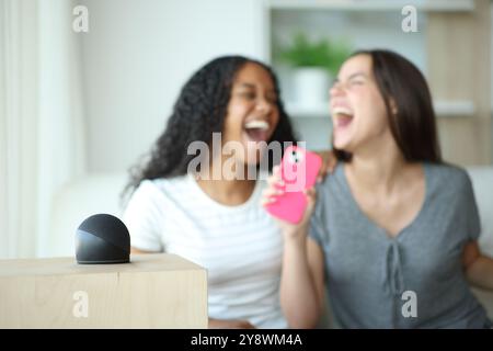 Haut-parleur intelligent jouant de la musique et des amis chantant avec le téléphone portable à la maison Banque D'Images