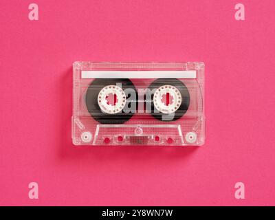 La cassette audio transparente sur fond rose évoque la nostalgie pour les amateurs de musique rétro, symbolisant un mélange de technologie old-School et de temps Banque D'Images