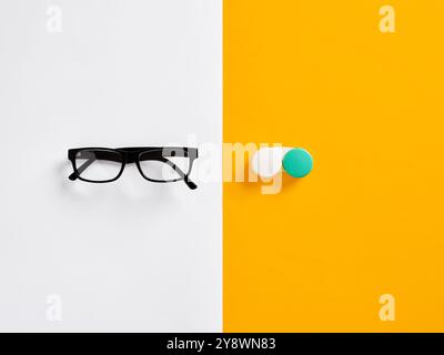 Paire de lunettes et un étui de lentilles de contact sur fond jaune blanc. Le choix entre différentes méthodes de correction de la vue. Banque D'Images