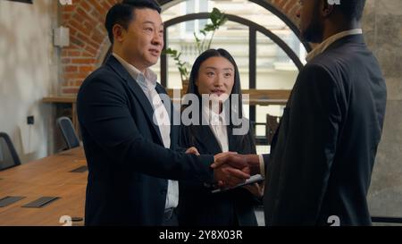 Trois entreprises multiraciales personnes multiethniques collègues diversité collègues dans le bureau réunion de deux hommes d'affaires hommes d'affaires Africains Asiatiques hommes parlent poignée de main Banque D'Images