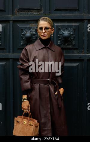 Caro Daur portant une veste-manteau longue en cuir rouge/marron/bordeaux, un pull col tortue noir, un sac birkin marron daim chez Hermès Paris Fashion week SS25 Banque D'Images