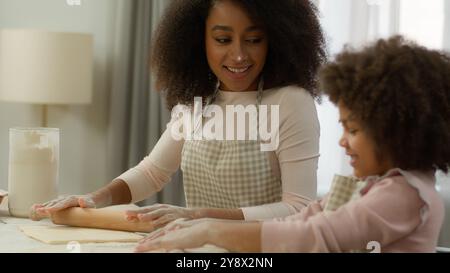 Famille heureuse à la cuisine cuisiner ensemble souriant maman afro-américaine femme mère sale visage dans la farine blanche enseignant mignon enfant fille préscolaire Banque D'Images