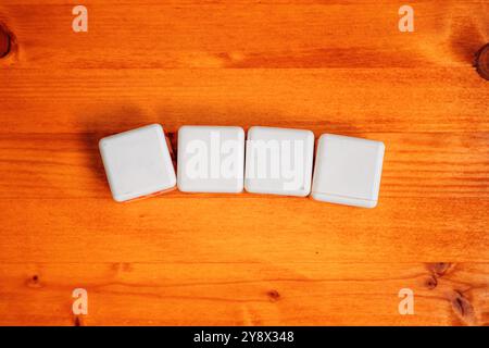 Quatre cubes blancs vierges sur la table en bois comme espace de copie de maquette, mise au point sélective Banque D'Images