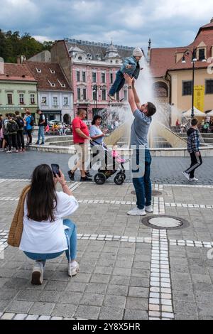 Une famille prenant des photos sur la place du Conseil (Piața Sfatului), Brașov, Transylvanie, Roumanie Banque D'Images