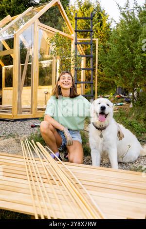 Menuisière femelle avec son chien construisant une serre en bois Banque D'Images