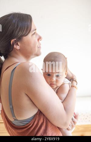 Une femme tient un bébé dans ses bras dans une pose détendue et réfléchie. Le bébé est calme. Banque D'Images