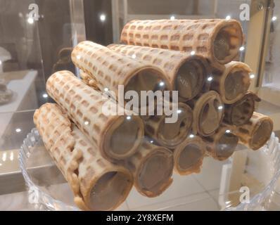 Les rouleaux de gaufre avec de la crème de lait condensée se trouvent dans une pile dans la fenêtre d'un magasin de café. Banque D'Images