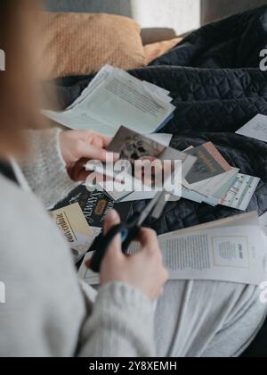 Femme scrapbooking coupant des magazines pour une planche de vision avec des ciseaux dans un cadre confortable Banque D'Images