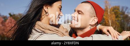 Un couple embrasse chaleureusement dans les couches d'automne, appréciant l'autre compagnie au milieu des feuilles vibrantes. Banque D'Images