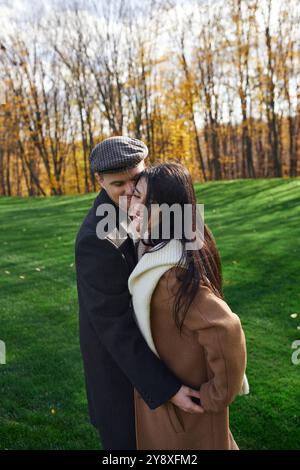 Un couple partage une étreinte joyeuse, habillé chaudement pour une belle journée d'automne. Banque D'Images