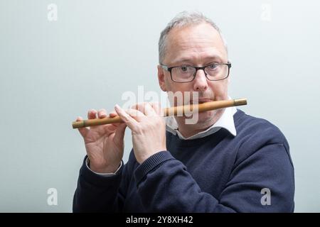 Homme d'âge moyen, habillé de façon décontractée, cheveux grisants, portant des lunettes, musicien expérimenté, jouer au feu traditionnel en bois de boîte. Banque D'Images