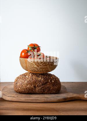 Tomates fraîches, pain de grains entiers sur une planche de bois rustique avec un couteau brillant Banque D'Images