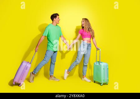 Photo pleine grandeur de deux jeunes gentils tiennent la valise des bras isolé sur fond de couleur jaune vif Banque D'Images