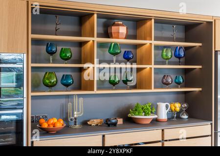 Verrerie sur étagères dans une cuisine design moderne dans le Gloucestershire, Angleterre, Royaume-Uni Banque D'Images